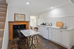 a kitchen with a table and a fireplace at Lythgo's Row Colonial Cottages in Pontville