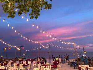 un grupo de personas sentadas en sillas en una playa con luces en Sinsamut Koh Samed, en Ko Samed