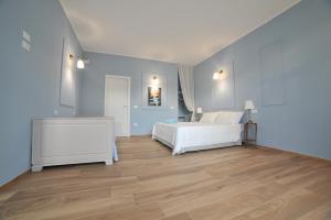 1 dormitorio con cama blanca y suelo de madera en B&B L'OFFICINA DEI SOGNI en Poggio Morello