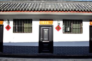 una casa blanca con una puerta negra y dos ventanas en Qufu Garden Hotel, en Qufu