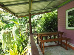 un banco de madera sentado bajo un dosel en un porche en Pattama Resort @ KeereWong, en Kiriwong