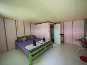 Dormitorio pequeño con cama púrpura y mesa en Pattama Resort @ KeereWong, en Kiriwong