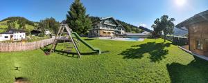 un parque infantil con un tobogán en un patio verde en Appartements Tannenhof, en Wagrain