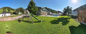 a playground with a slide in a green yard at Appartements Tannenhof in Wagrain