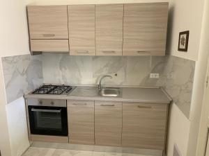 a kitchen with wooden cabinets and a stove top oven at Stabilimento Balneare Città Giardino - Casa Vacanza in Viareggio