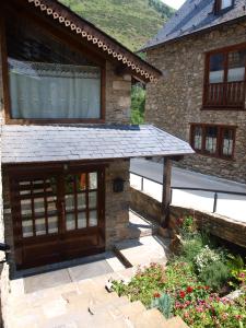 a stone house with a wooden door and a patio at Hotel Ço De Pierra in Betrén