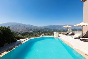 een zwembad met uitzicht op de bergen bij Villa Galanis in Kalamitsi Amygdali
