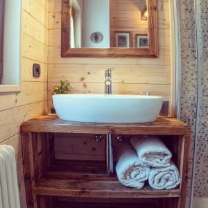 uma casa de banho com um lavatório e toalhas num toucador de madeira em I Larici Camping Lodge em Ossana