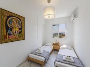 Habitación con 2 camas y una pintura en la pared. en Mackenzie Leo Seafront Suite, en Lárnaca