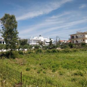 a field with a fence and buildings in the background at Nea Stira Studios Kondilia in Nea Stira