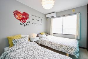 松戶的住宿－松戸 テイクファイブ - 水色1DK Nomad松戸宿015，墙上有心的房间里,有两张床