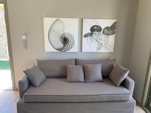 a couch in a living room with three pictures on the wall at Costa D' Ifesto in Agios Ioannis Kaspaka