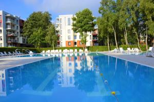 a large swimming pool with white chairs and a building at Apartament H204 z widokiem na basen in Kołobrzeg