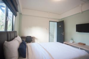 um quarto com uma cama branca e uma televisão de ecrã plano em Baan Ploy In em Chiang Mai