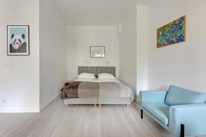 a bedroom with a bed and a blue couch at Grand Apartments - Studio Apartment 50 m from Monte Cassino in Sopot