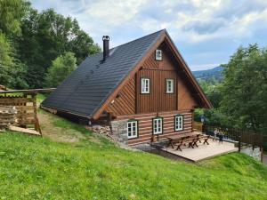 ein Haus mit einem schwarzen Dach und einer Holzterrasse in der Unterkunft Chalupa MODŘÍN in Horní Maršov