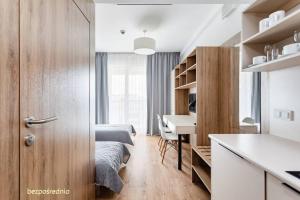 a bedroom with a bed and a desk and a kitchen at Apartament w Warszawie dedykowany parking podziemny w cenie, WiFi, AC, blisko centrum New apartment in Warsaw finished to a high specification fitted out to a high standard on the 7th floor, WiFi, underground parking price included in Warsaw +30 photos