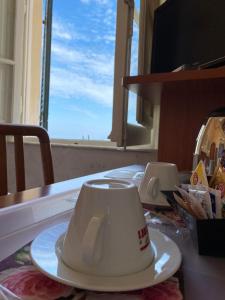 une tasse de café assise sur une table devant une fenêtre dans l'établissement Hotel Italia, à Marina di Massa