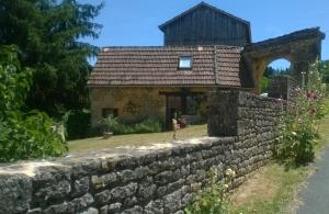 a stone house with a stone wall at Chambre d'hôtes Lasserre in Saint-Amand-de-Coly