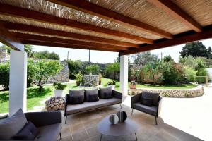 patio con divano e sedie sotto un pergolato in legno di Masseria San Rocco a Gallipoli