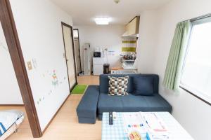 松戸 テイクファイブ 1DK Nomad松戸宿056 في ماتسودو: غرفة معيشة مع أريكة زرقاء ومطبخ