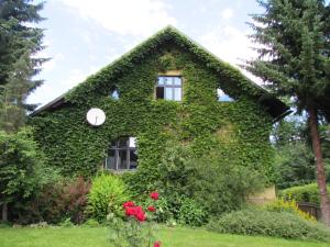 a house covered in ivy with a clock on it at Dům u rybníka in Nýdek