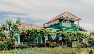 a green house with a balcony in a yard at Căsuţa de lângă Lac in Saharna Nouă