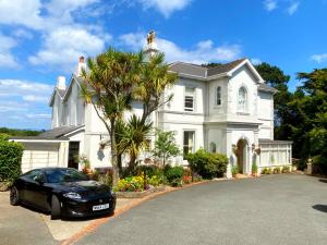 un coche negro estacionado frente a una casa blanca en Muntham Luxury Holiday Apartments en Torquay