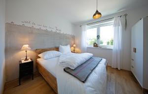 a bedroom with a bed with white sheets and a window at Ferienwohnungen Waltraud Trinker, Haus in Haus im Ennstal