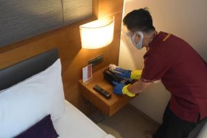 un homme dans une chambre d'hôtel avec un masque et un lit dans l'établissement Sotis Residence Pejompongan, à Jakarta