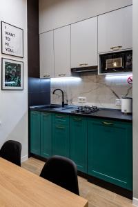 Emerald Lux Apartment. LiveInLviv في إلفيف: مطبخ مع دواليب خضراء وطاولة خشبية