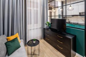 ein Wohnzimmer mit einem Sofa und einem Flachbild-TV in der Unterkunft Emerald Lux Apartment. LiveInLviv in Lwiw