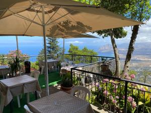 a patio with tables and chairs and an umbrella at Hotel Villa San Giovanni in Erice
