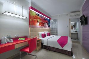 a bedroom with a bed and a desk with a red chair at favehotel Premier Cihampelas in Bandung +20 photos