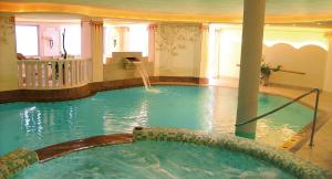 a large swimming pool with a fountain in a hotel at Hotel Ortler in Tirolo