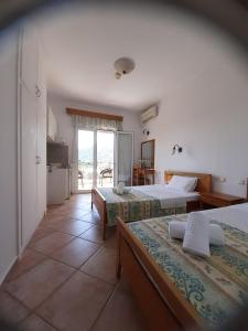 a hotel room with two beds and a window at Nostos Studios Golden Beach in Chrysi Ammoudia
