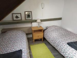 two beds in a room with a nightstand between them at Ar Parkou in Plonévez-du-Faou