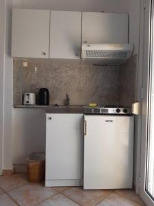 a kitchen with white cabinets and a sink at Nostos Studios Golden Beach in Chrysi Ammoudia