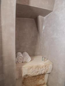 un bagno con asciugamani arrotolati su una mensola di Ariad Collection a Ostuni
