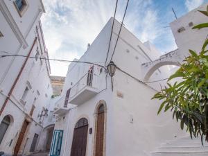 a white building with a balcony on a street at Ariad Collection in Ostuni