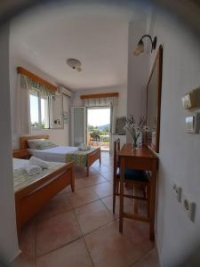 une chambre avec deux lits, une table et un bureau dans l'établissement Nostos Studios Golden Beach, à Chrysi Ammoudia