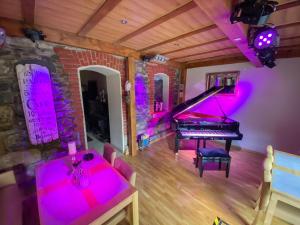 a room with a piano and a dining room with pink lights at Pension Oybin in Kurort Oybin