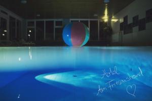 a large swimming pool with a ball in the background at Hotel Am Friesenstrand in Butjadingen