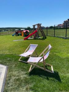 two lawn chairs sitting in the grass in a park at Apartamenty Lagos in Karwia