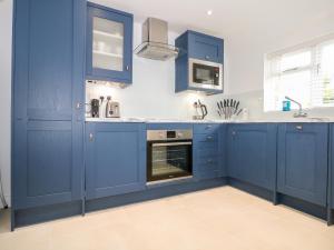 een keuken met blauwe kasten en een oven bij Stables Cottage in Heathfield
