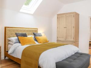 a bedroom with a bed with yellow pillows and a cabinet at Stables Cottage in Heathfield