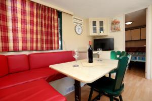 a living room with a red couch and a table with wine glasses at Olive garden mobil home - Trogir in Trogir