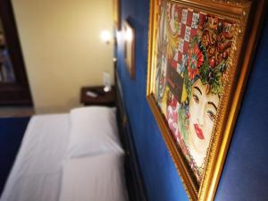 una pintura de una mujer en una pared junto a una cama en Del Centro, en Enna