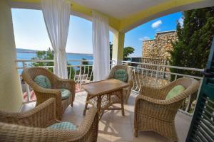 a porch with wicker chairs and a table on a balcony at Apartman Rosa 2 in Kustići