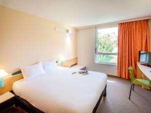ein Hotelzimmer mit einem großen weißen Bett und einem Fenster in der Unterkunft ibis Perpignan Nord Rivesaltes in Rivesaltes